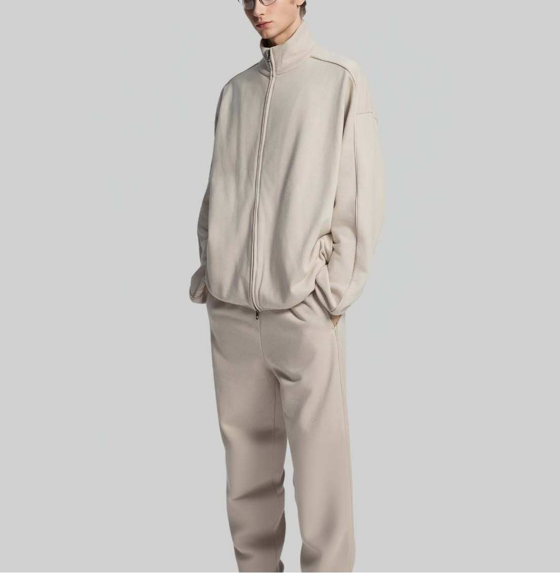 Person wearing a beige tracksuit from front and back views on a white background